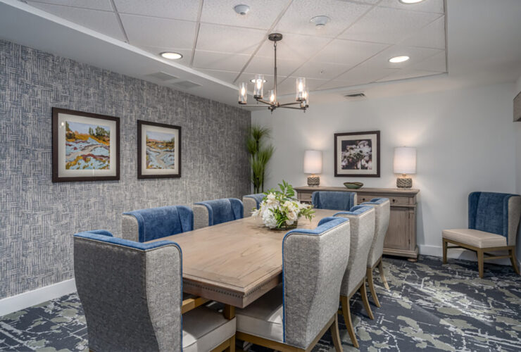 Dining room with elegant chairs, soft lighting, artwork, and floral centerpiece for gatherings.