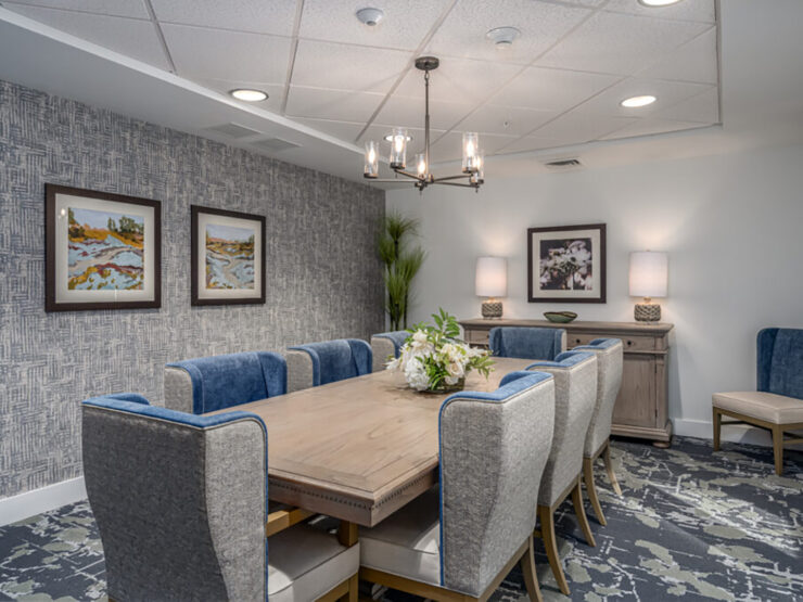 Dining room with elegant chairs, soft lighting, artwork, and floral centerpiece for gatherings.