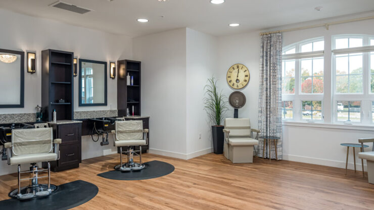 Bright and inviting salon area with comfortable chairs and warm natural light from large windows.