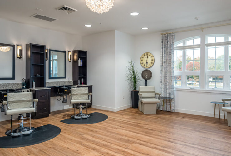 Bright and inviting salon area with comfortable chairs and warm natural light from large windows.