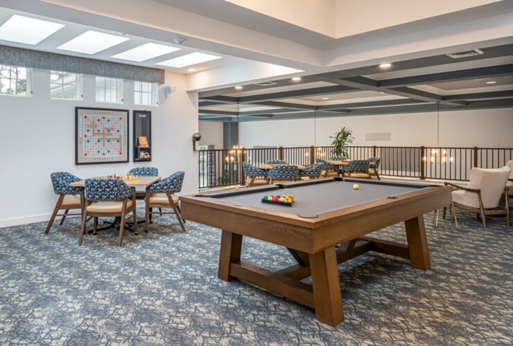Bright game room with billiards, card tables, and comfortable seating for socializing.