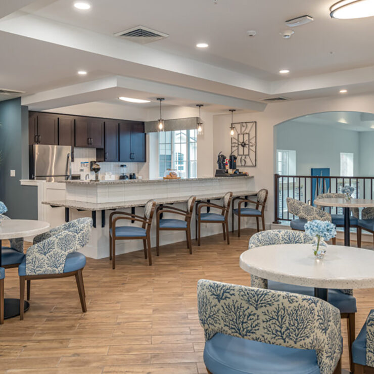 Bright, inviting communal dining area with seating and a fully equipped kitchen for resident gatherings.