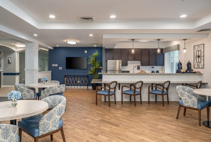 Open community room with comfortable seating, a kitchenette, and warm wood flooring.