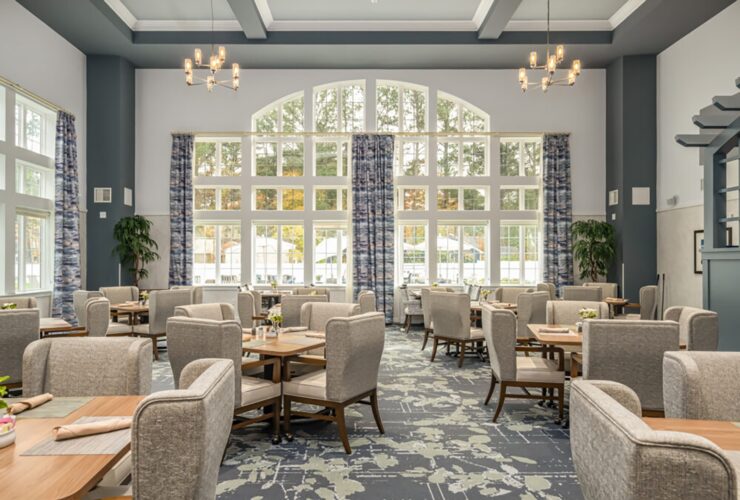 Bright, inviting dining area with comfortable seating, large windows, and elegant lighting fostering community.