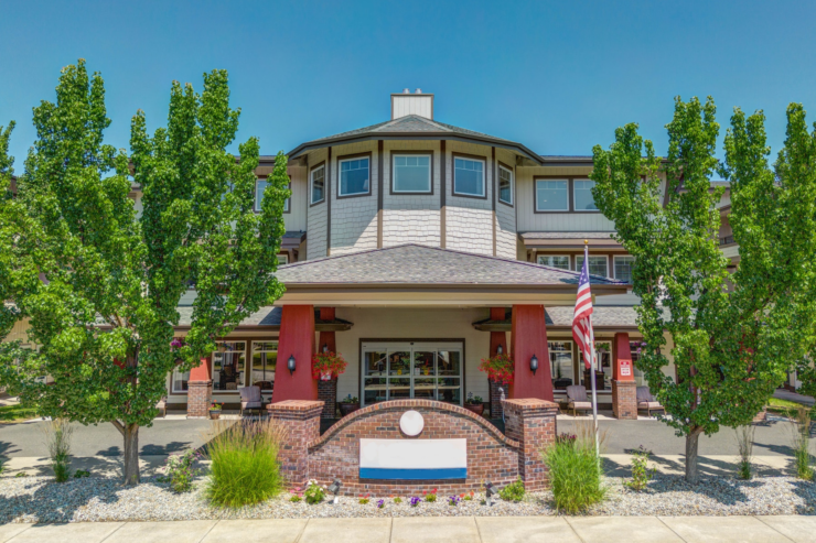 Bright entrance of a welcoming retirement community with seating areas and lush greenery.