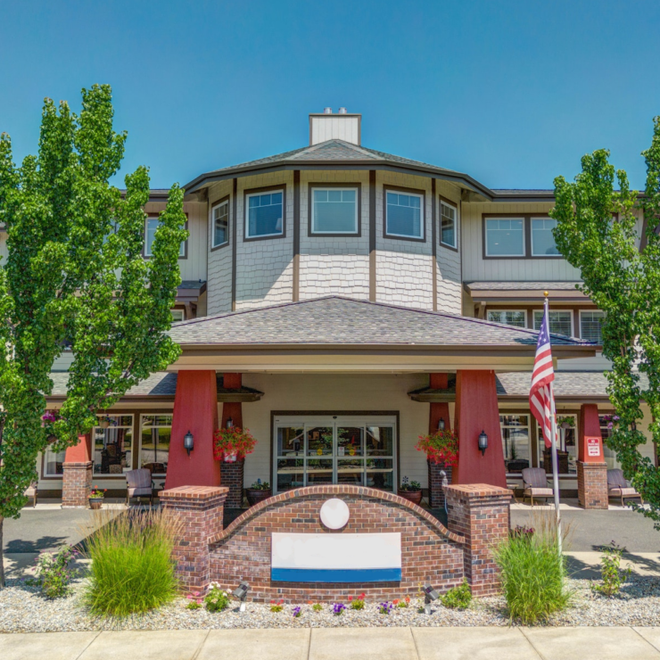Bright entrance of a welcoming retirement community with seating areas and lush greenery.