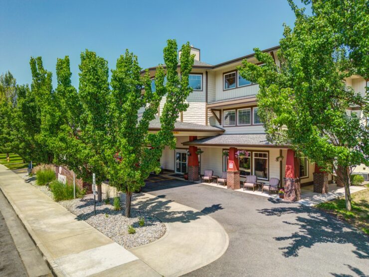Well-maintained retirement home entrance surrounded by greenery and inviting outdoor seating.