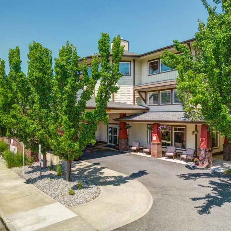 Well-maintained retirement home entrance surrounded by greenery and inviting outdoor seating.