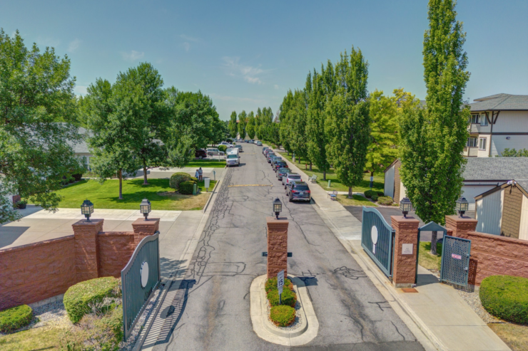 Gated entrance to a vibrant community with lush trees and welcoming sidewalks.
