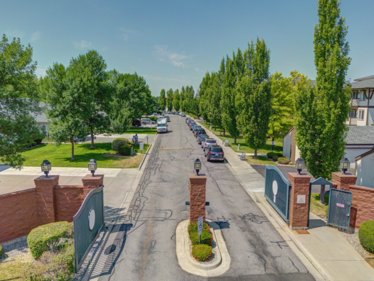 Gated entrance to a vibrant community with lush trees and welcoming sidewalks.