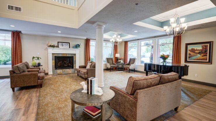 Sunlit lounge with comfortable seating, fireplace, piano, and warm inviting decor for community gatherings.