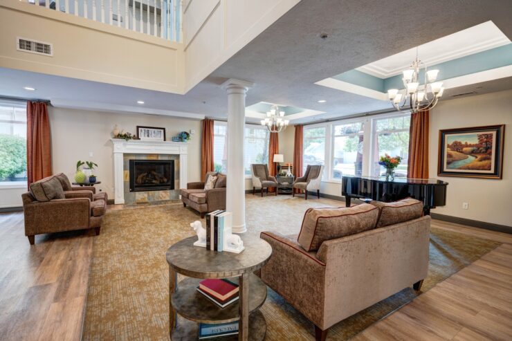 Sunlit lounge with comfortable seating, fireplace, piano, and warm inviting decor for community gatherings.
