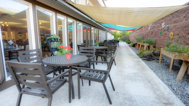 Outdoor patio with shaded seating, flowers, and a peaceful garden walkway.