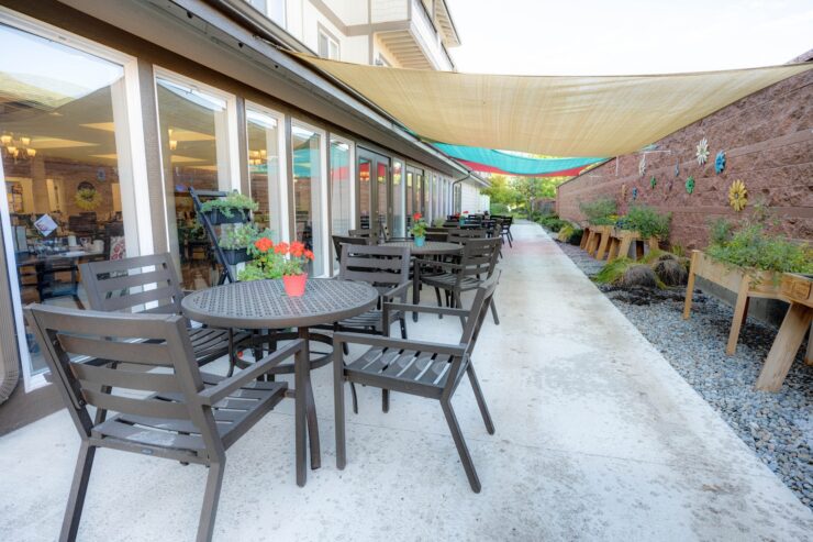 Outdoor patio with shaded seating, flowers, and a peaceful garden walkway.