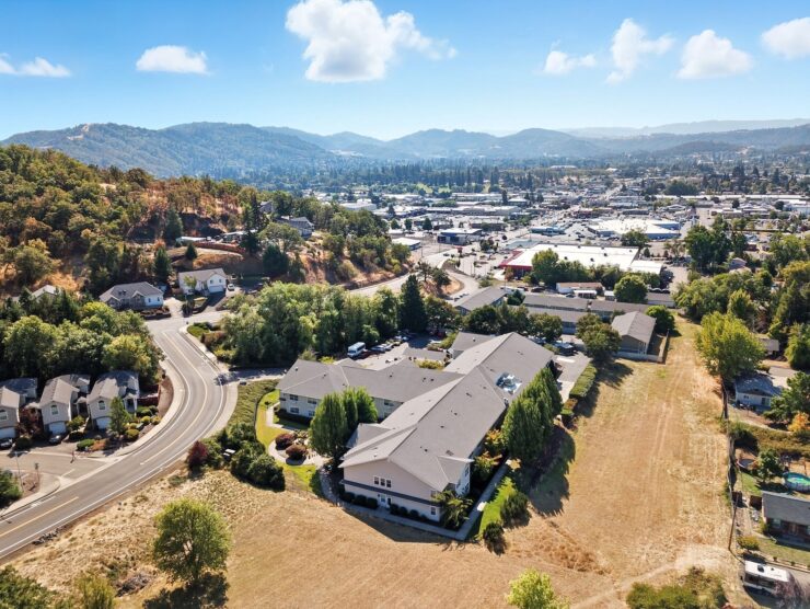 Retirement community nestled among trees with mountain views and a vibrant town nearby.