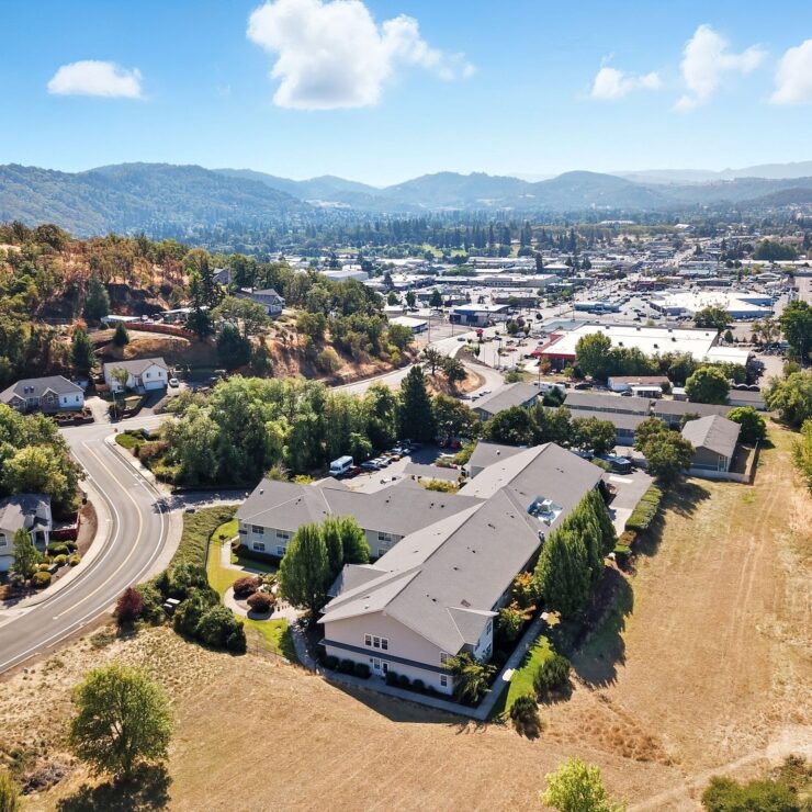 Retirement community nestled among trees with mountain views and a vibrant town nearby.