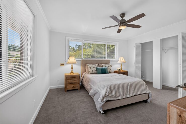 Bright bedroom with plush bed, soft pillows, bedside lamps, ceiling fan, and open closet space