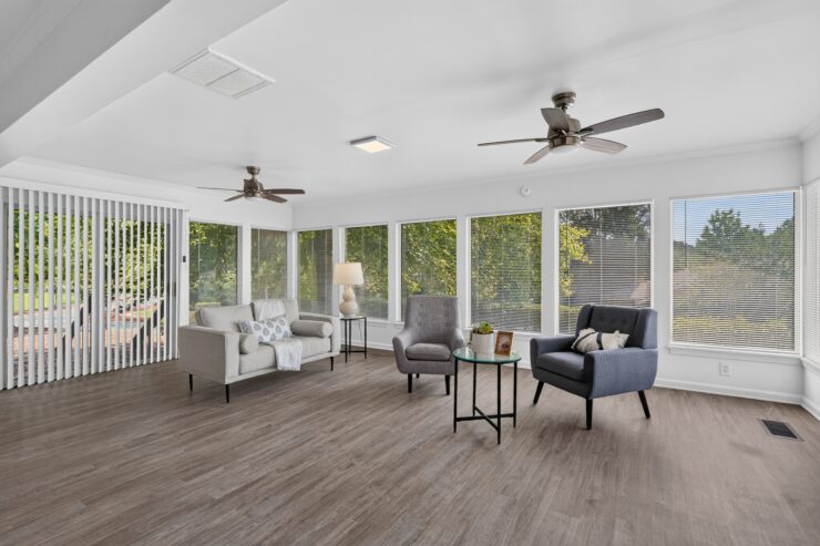 Sunlit living room with comfortable seating, large windows, and a welcoming atmosphere.