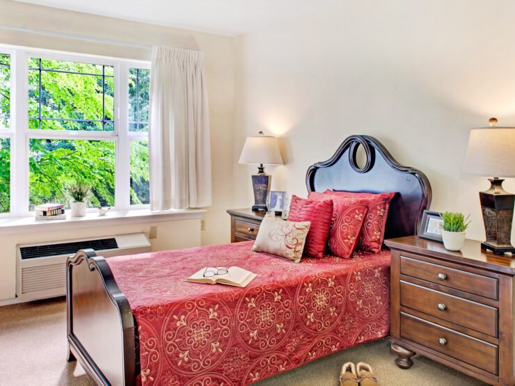 Sunlit bedroom with warm wood furniture, vibrant bedding, and peaceful garden views.