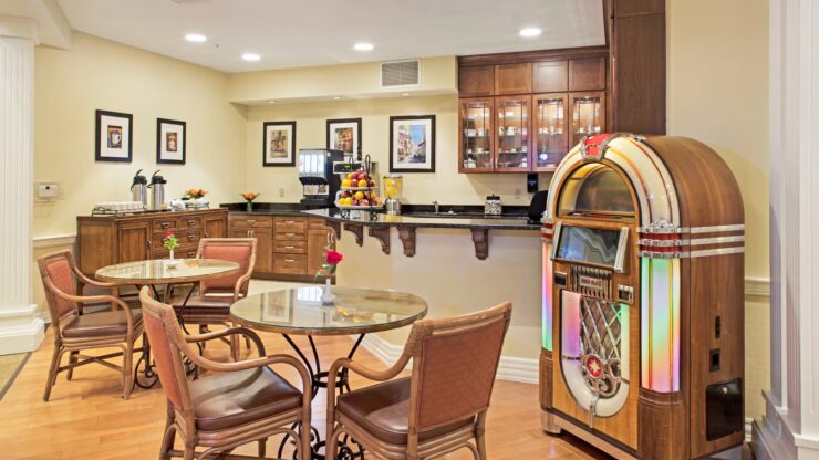 Dining area with warm wood furnishings, a vintage jukebox, and inviting seating for residents.