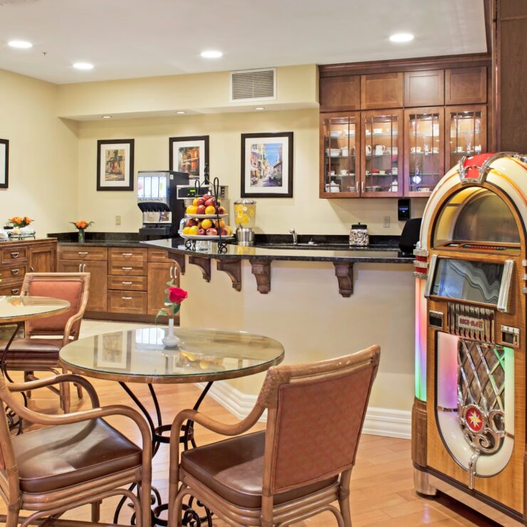 Dining area with warm wood furnishings, a vintage jukebox, and inviting seating for residents.