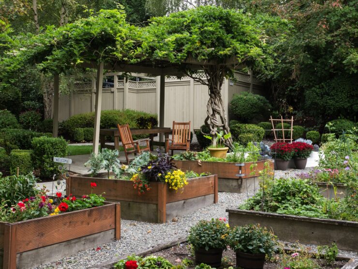 Lush garden with raised flower beds, wooden seating, and a vine-covered pergola for relaxation.