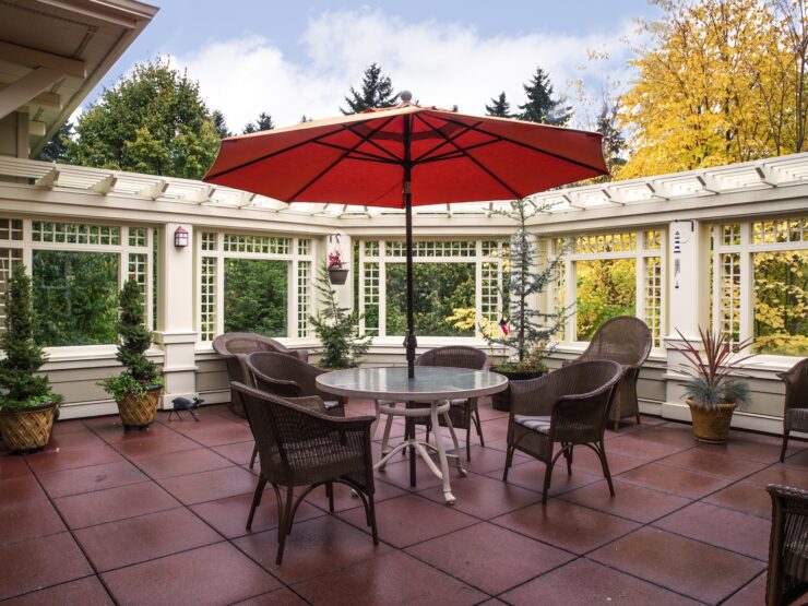 Outdoor seating area with umbrella, surrounded by greenery and comfortable chairs for gathering.