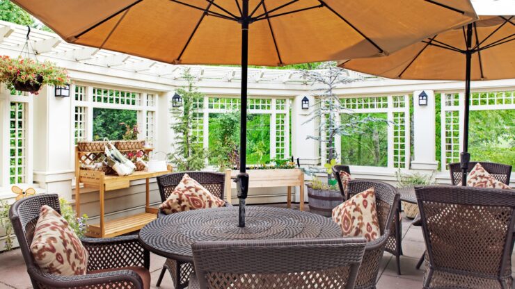 Patio seating area with umbrellas, comfortable chairs, and lush greenery for relaxation and community.
