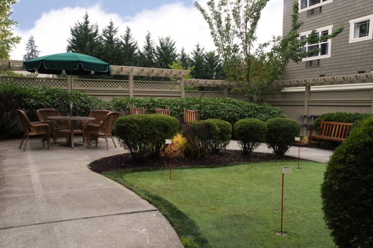 Outdoor seating area with putting green surrounded by greenery and comfortable chairs