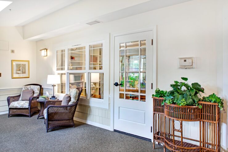 Inviting sun porch with cushioned wicker chairs, soft lighting, and lush greenery for relaxation.
