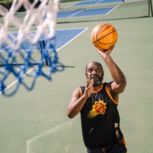 Active community member enjoying basketball on an outdoor court at a sunny day.