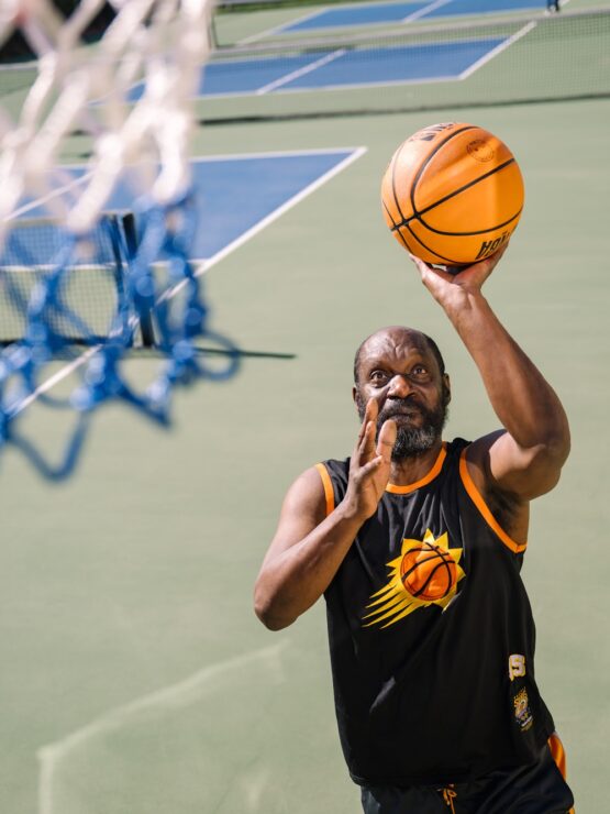 Active community member enjoying basketball on an outdoor court at a sunny day.