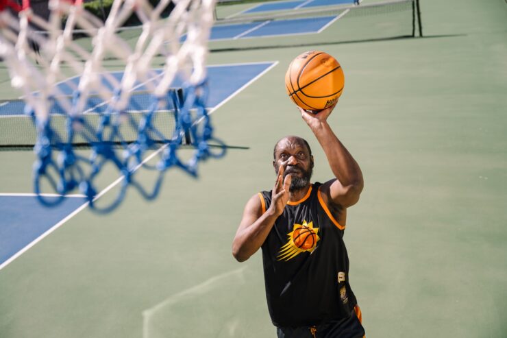 Active community member enjoying basketball on an outdoor court at a sunny day.