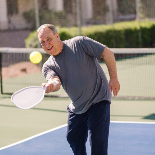 Man enjoying an active game of pickleball outdoors on a sunny day at the community courts.