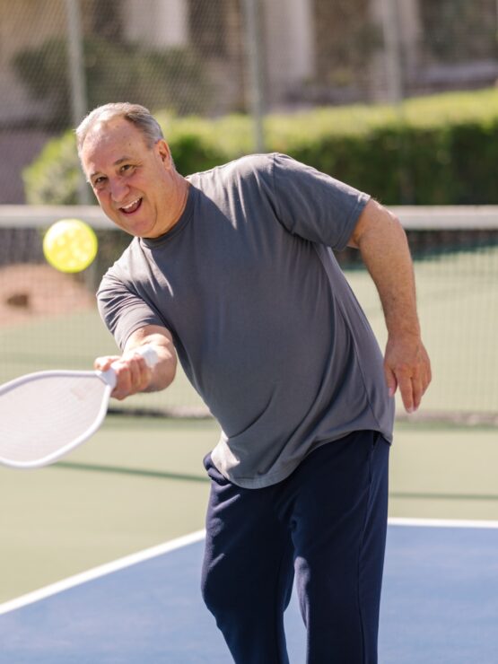 Man enjoying an active game of pickleball outdoors on a sunny day at the community courts.