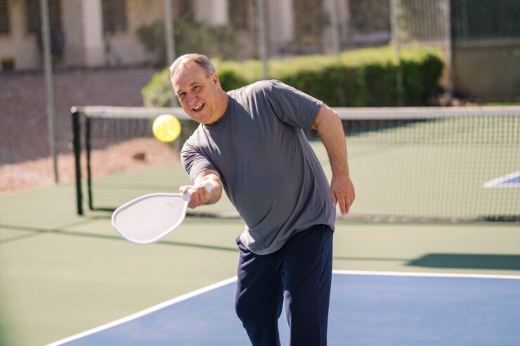 Man enjoying an active game of pickleball outdoors on a sunny day at the community courts.