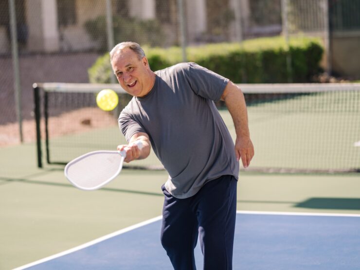 Man enjoying an active game of pickleball outdoors on a sunny day at the community courts.