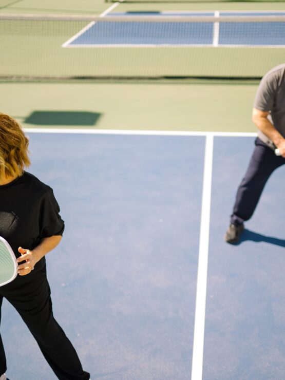 Two seniors enjoying a lively game of pickleball on a sunny outdoor court.