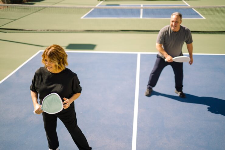 Two seniors enjoying a lively game of pickleball on a sunny outdoor court.