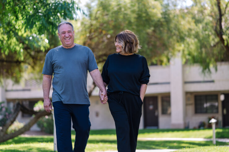 Mature couple enjoying a sunny walk together in a peaceful, green community setting.