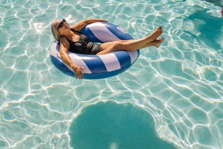 Senior woman in a swimsuit relaxing on a float in a bright, inviting swimming pool.