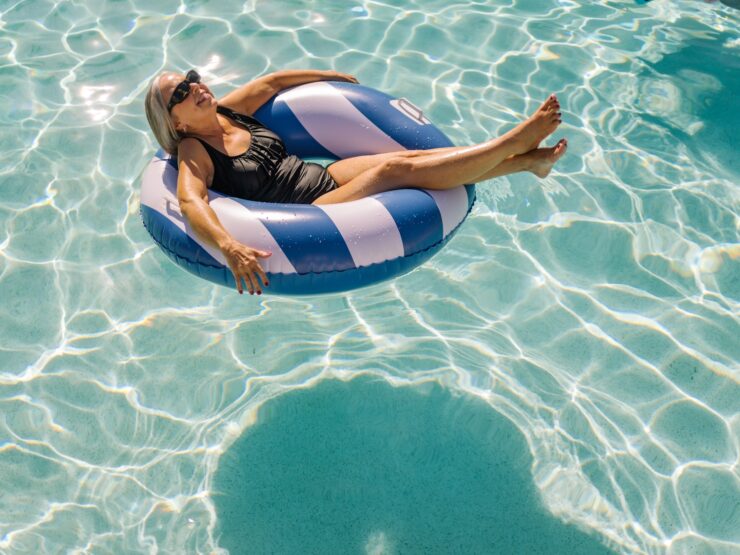 Senior woman in a swimsuit relaxing on a float in a bright, inviting swimming pool.