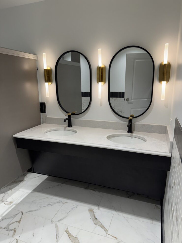 Modern bathroom with dual sinks, oval mirrors, and warm lighting for a welcoming feel.