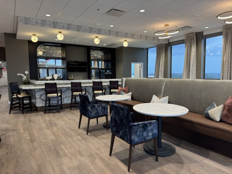 Modern lounge area with comfortable seating, large windows, and a welcoming community bar.