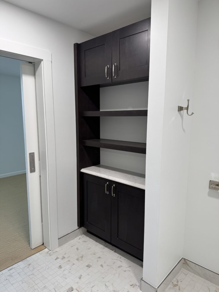 Elegant dark wood shelving and white marble countertop in a bright, welcoming common area.
