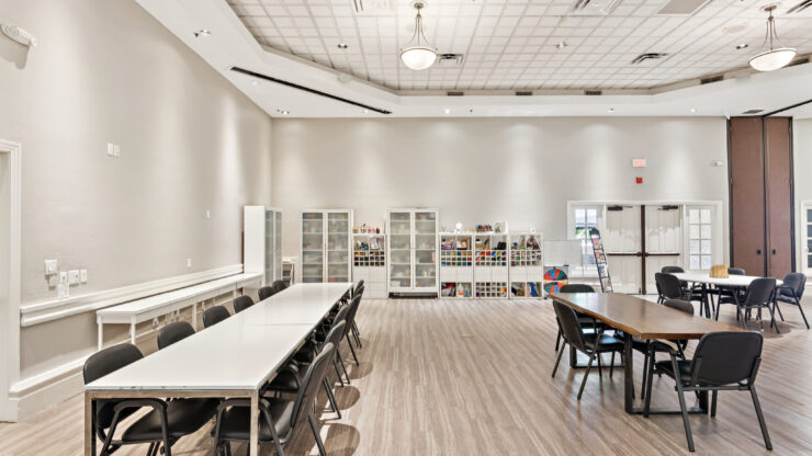 Bright, spacious activity room with tables, chairs, and art supplies for community engagement.