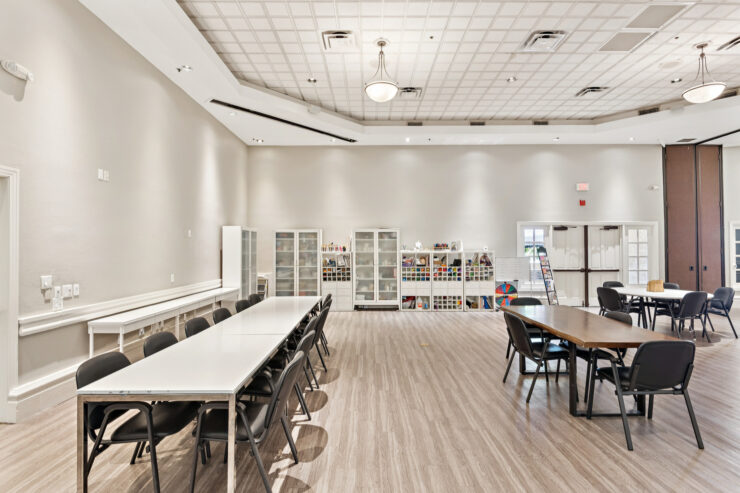 Bright, spacious activity room with tables, chairs, and art supplies for community engagement.