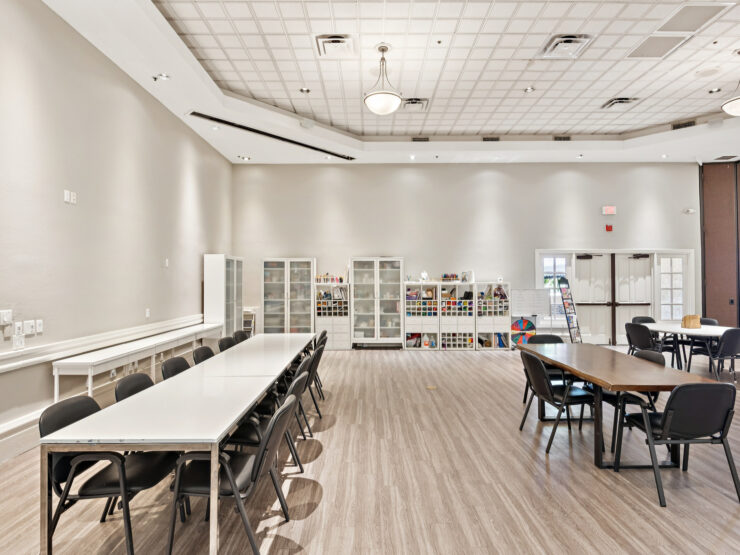 Bright, spacious activity room with tables, chairs, and art supplies for community engagement.
