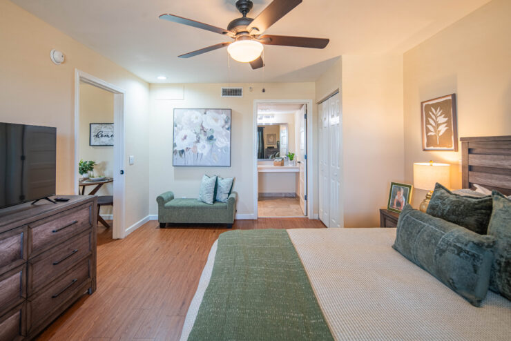 Bright bedroom with comfortable seating, warm lighting, and tasteful artwork for a welcoming atmosphere.
