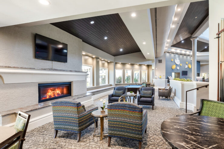 Bright and inviting lounge with fireplace, comfortable seating, and natural light fostering community.